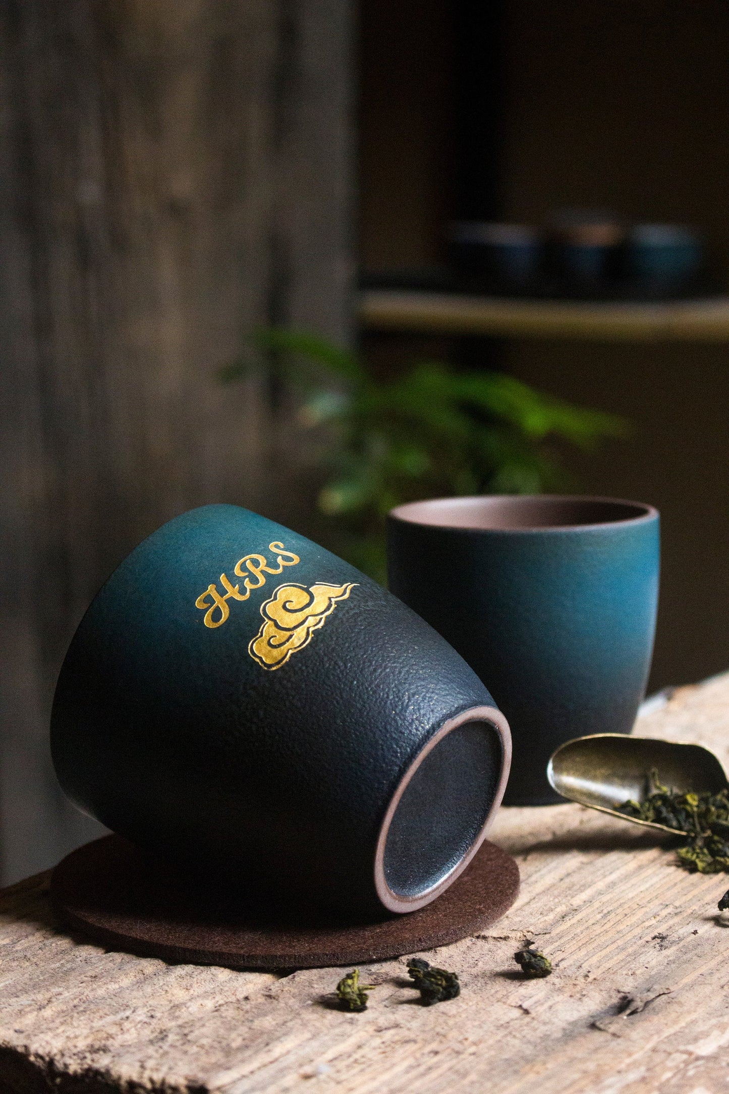 Handcrafted ceramic retro tea cups in deep green and blue gradient finish, cups on placemat and wooden surface