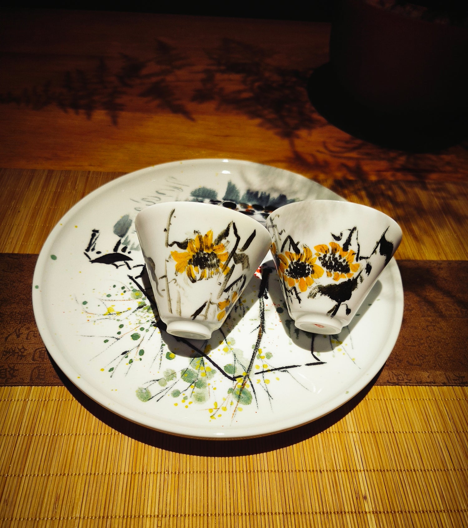 Close-up of hand-painted ceramic sunflower tea cups resting on a matching plate