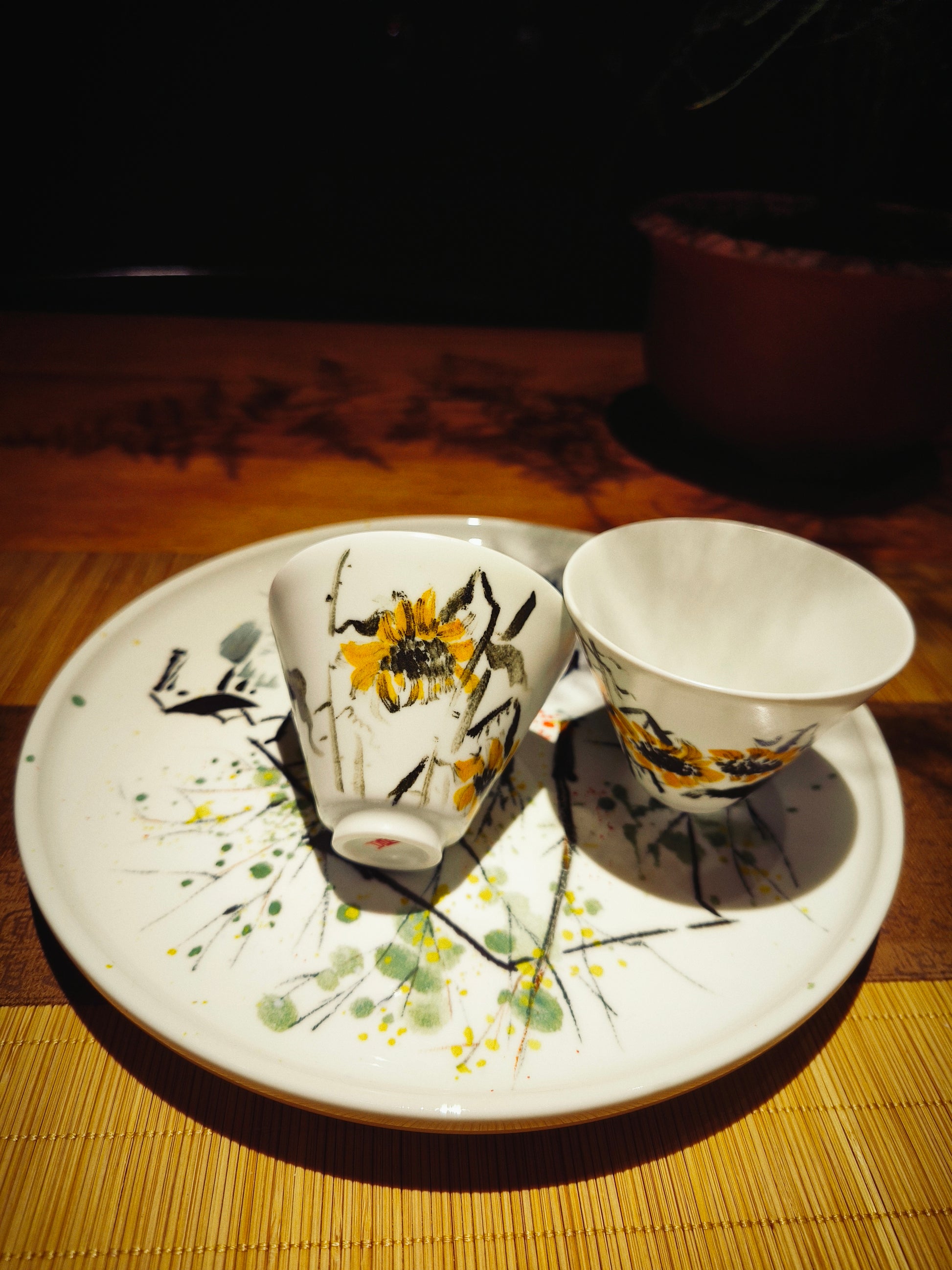 Detailed view of sunflower design on hand-painted ceramic plate and cups