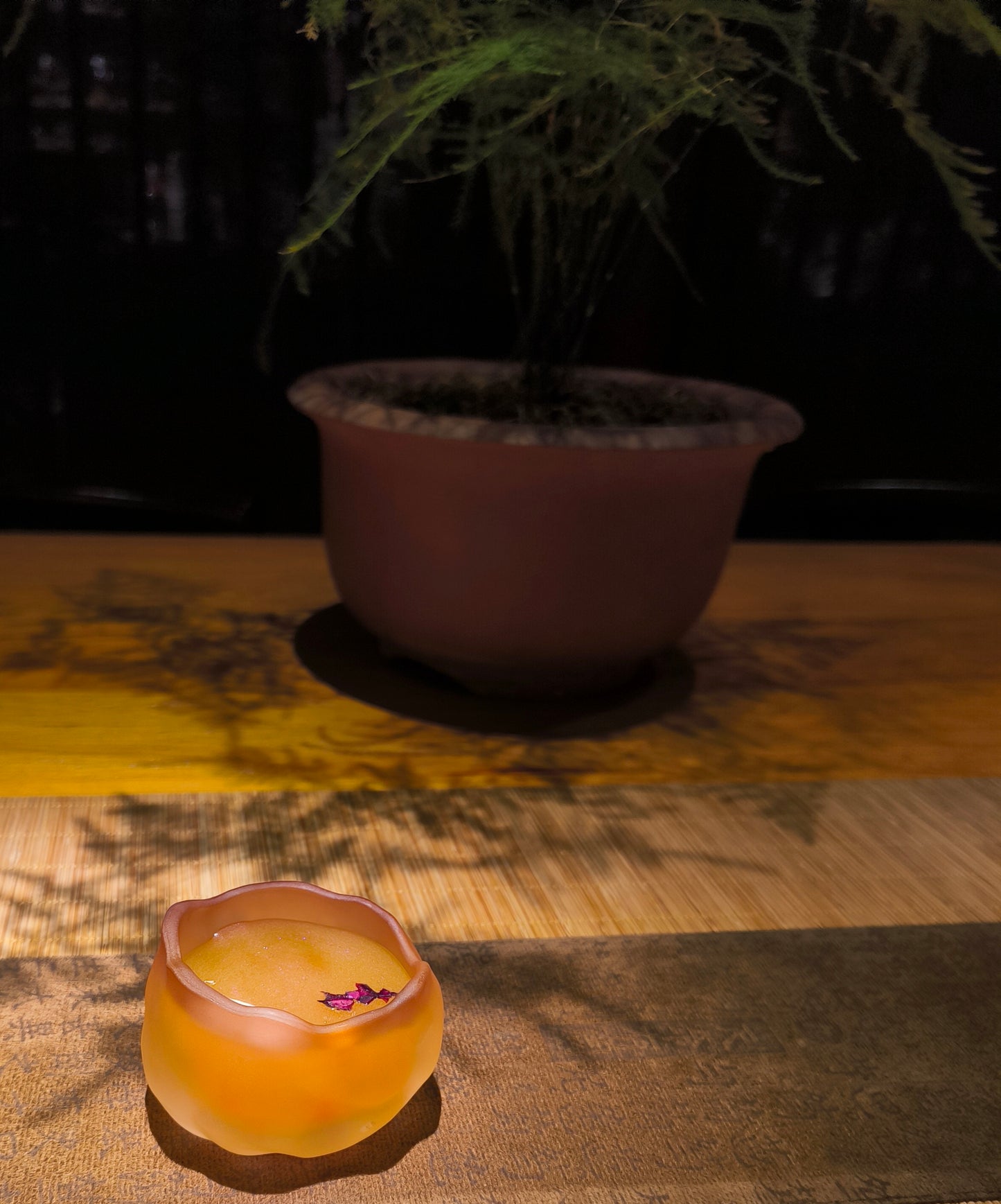 Flower shaped handcrafted ceramic wax melt cup with rose flower petals inside, placed on wooden surface with soft lighting