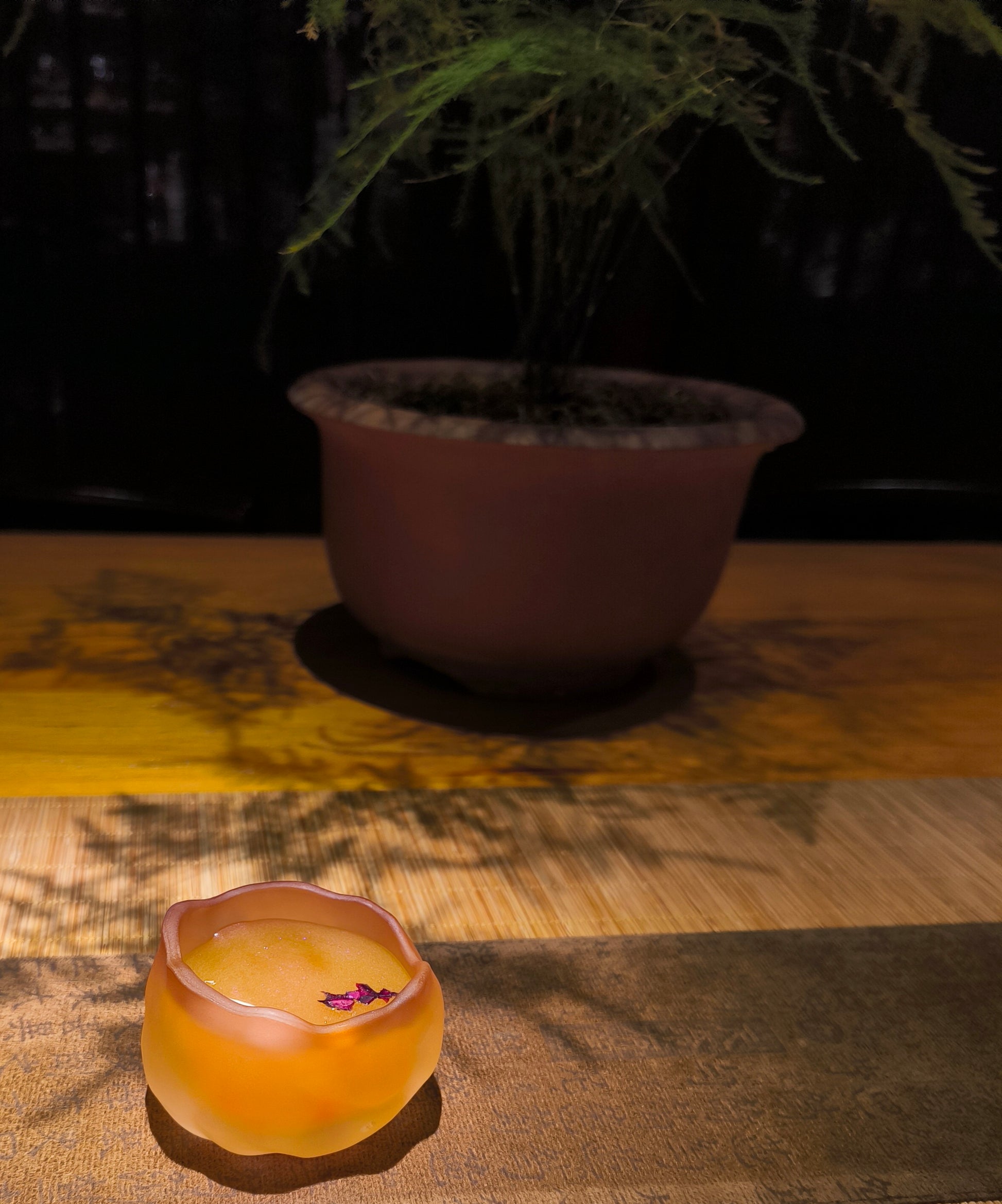Flower shaped handcrafted ceramic wax melt cup with rose flower petals inside, placed on wooden surface with soft lighting
