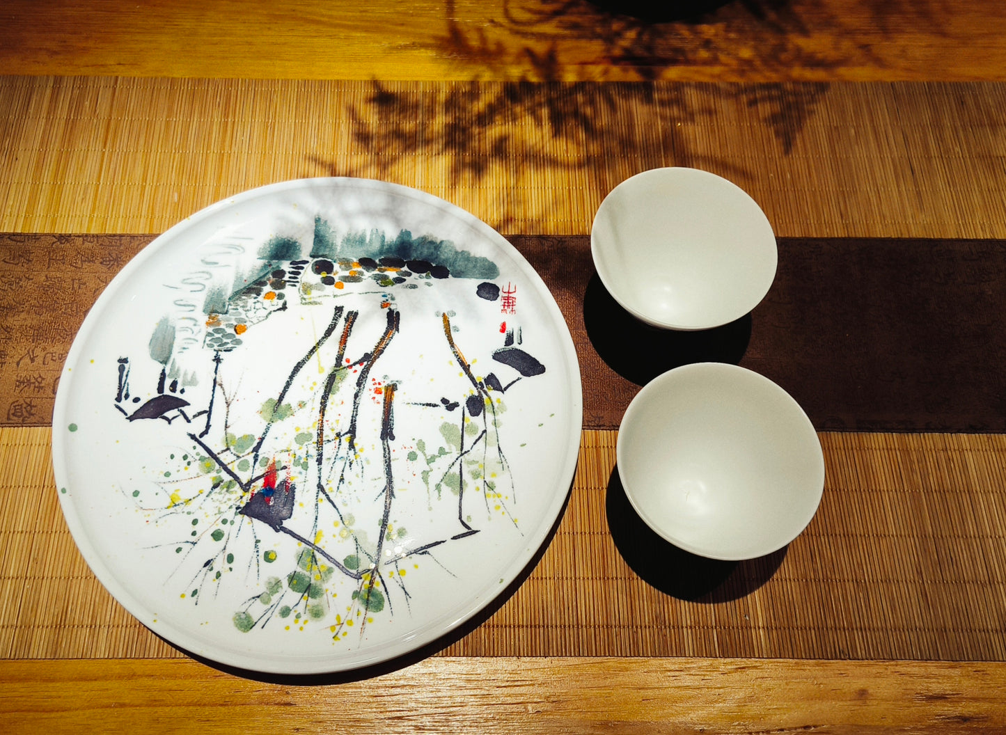 Hand-painted ceramic sunflower plate displayed with cups on wooden table