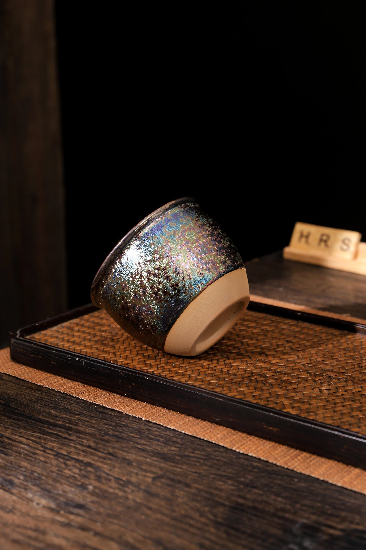 Handmade rainbow ceramic tea cup with shimmering finish on tray