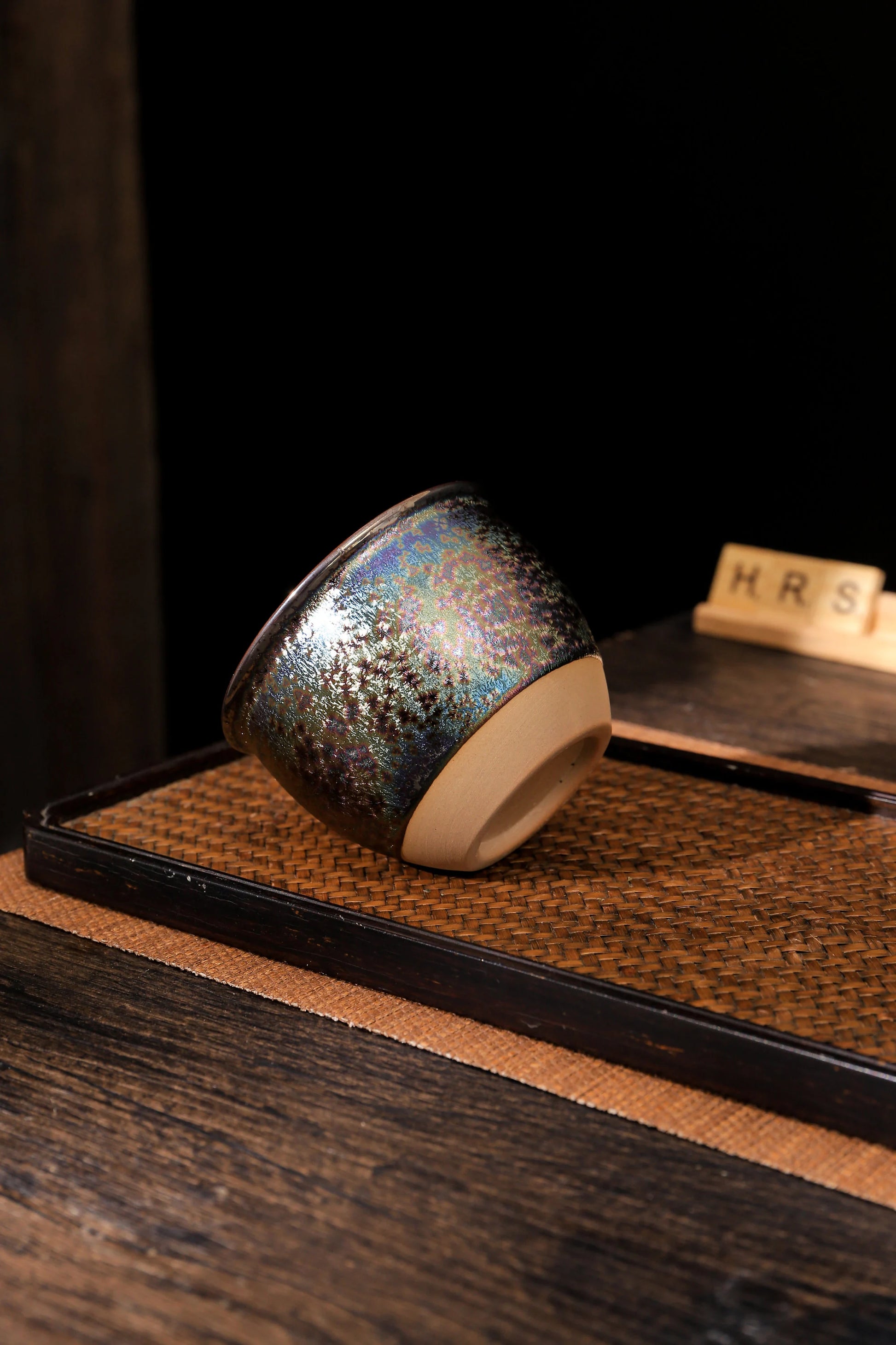 Handmade rainbow ceramic tea cup with shimmering finish on tray