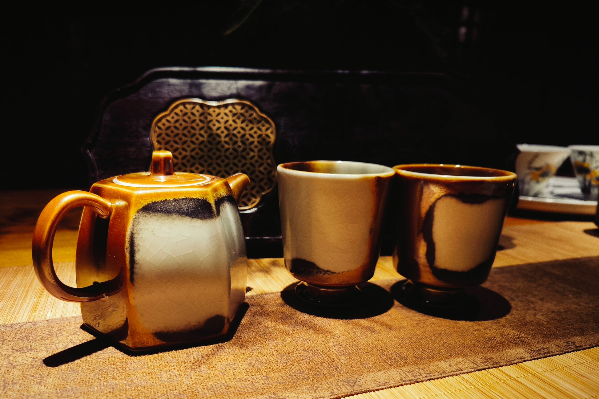 Retro-glazed ceramic teapot with matching cups displayed on tea table