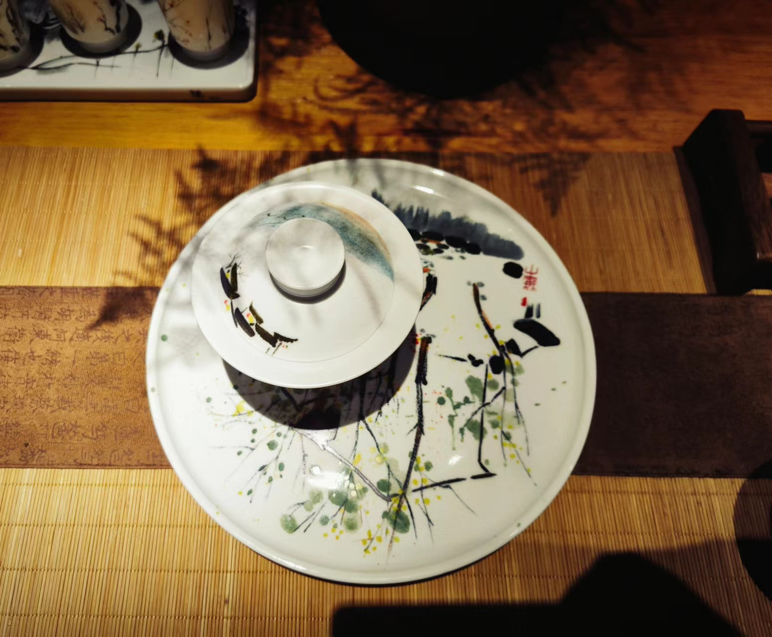 Top view of ceramic covered bowl gaiwan and an artistic serving plate featuring underglaze Chinese art