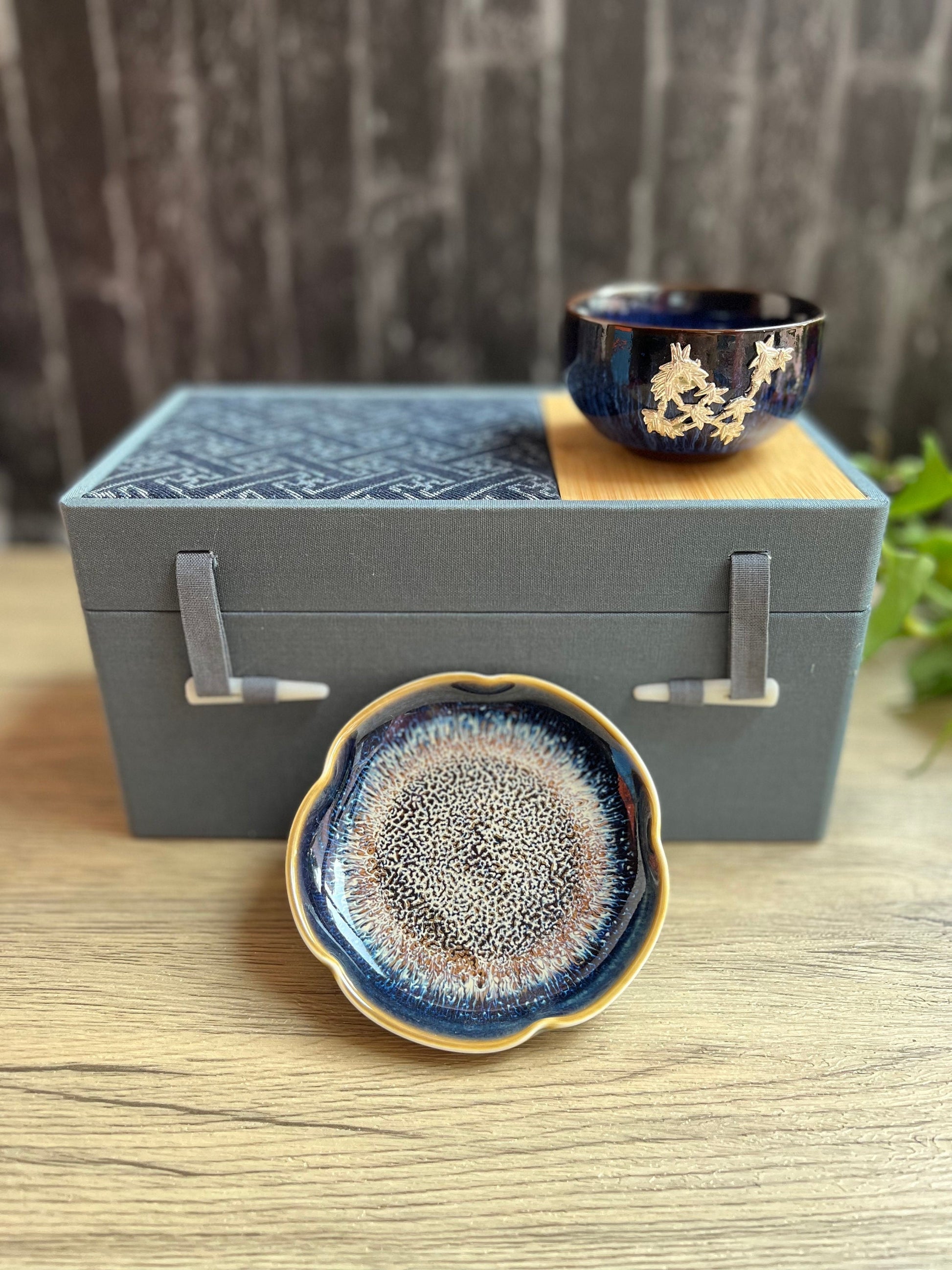 Blue floral tea cup and dish set elegantly placed on a decorative gift box.