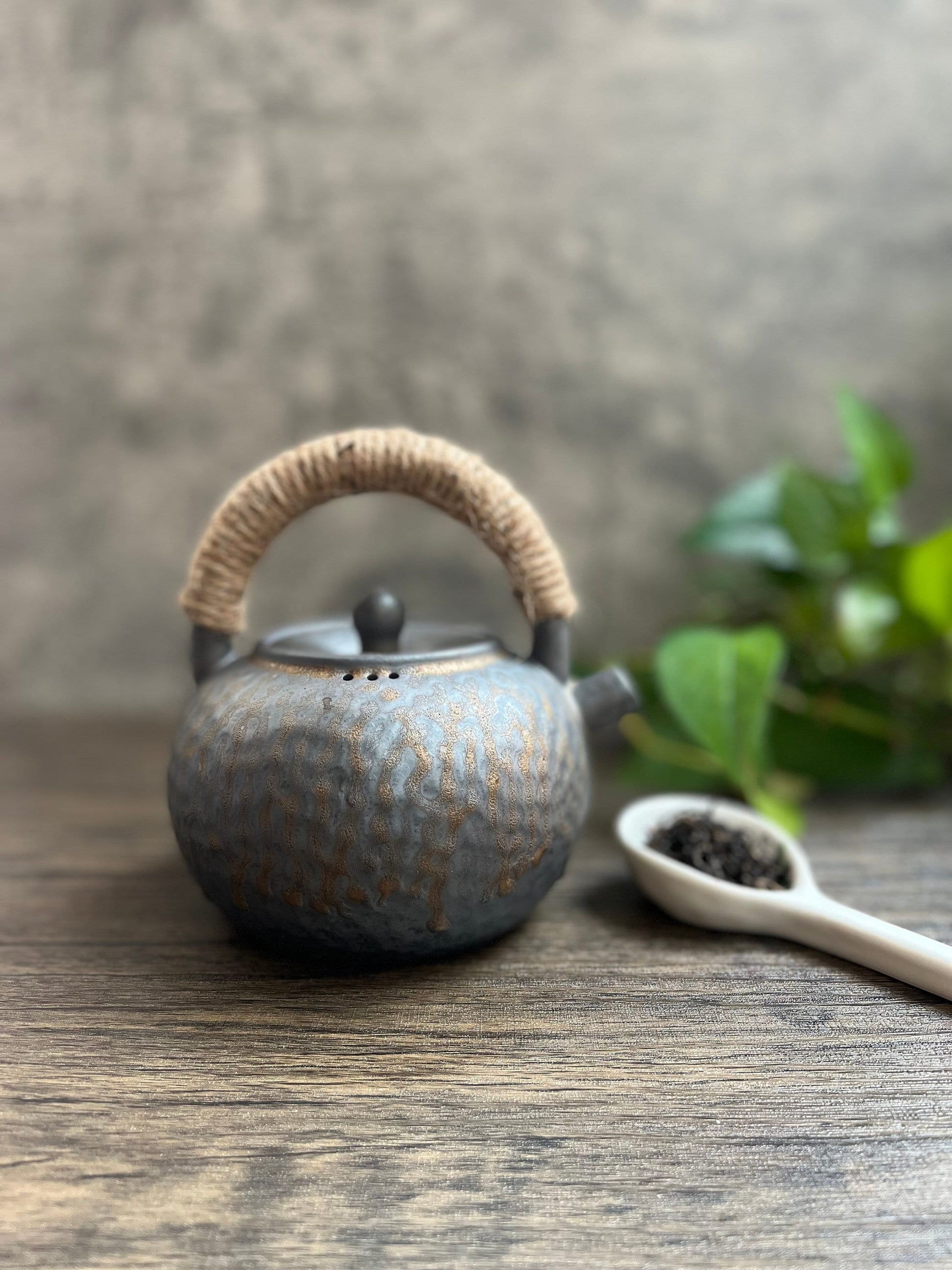 Close-up of textured ceramic teapot with natural rope wrapped handle