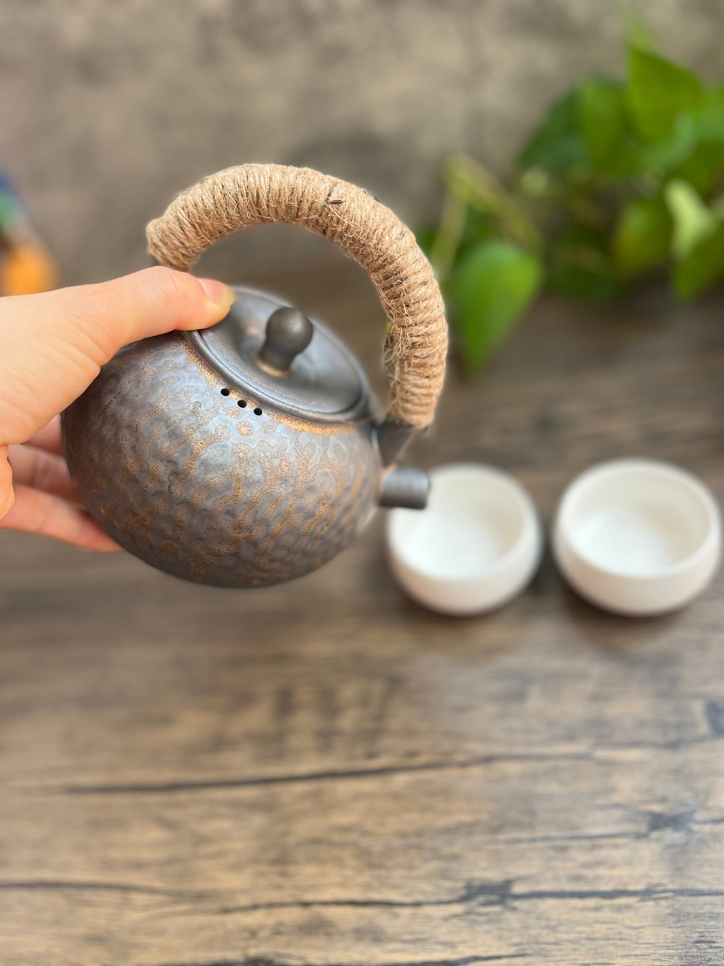 Hand pouring from Zen style ceramic water kettle with woven handle