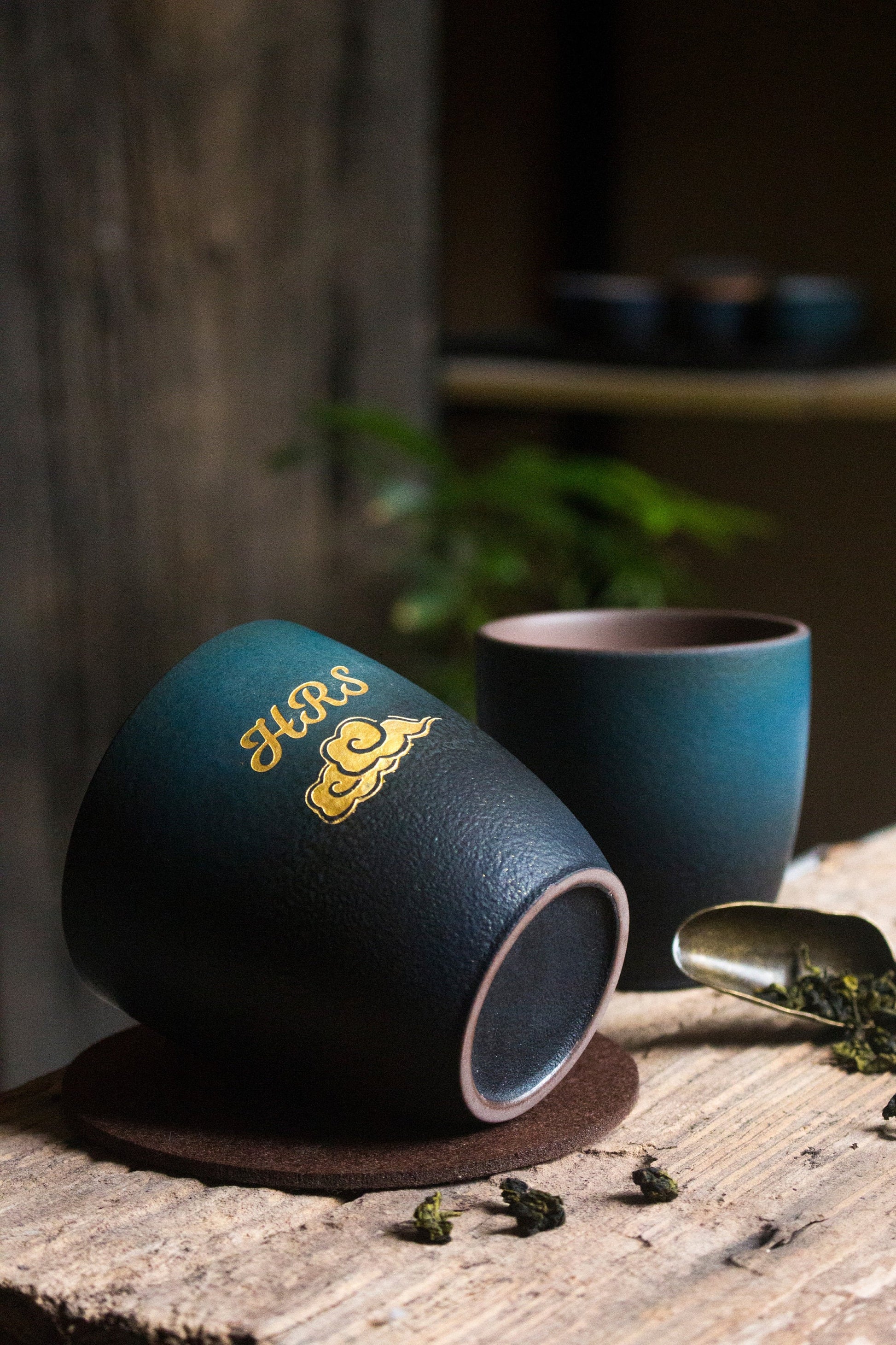 Handcrafted ceramic retro tea cups in deep green and blue gradient finish, cups on placemat and wooden surface