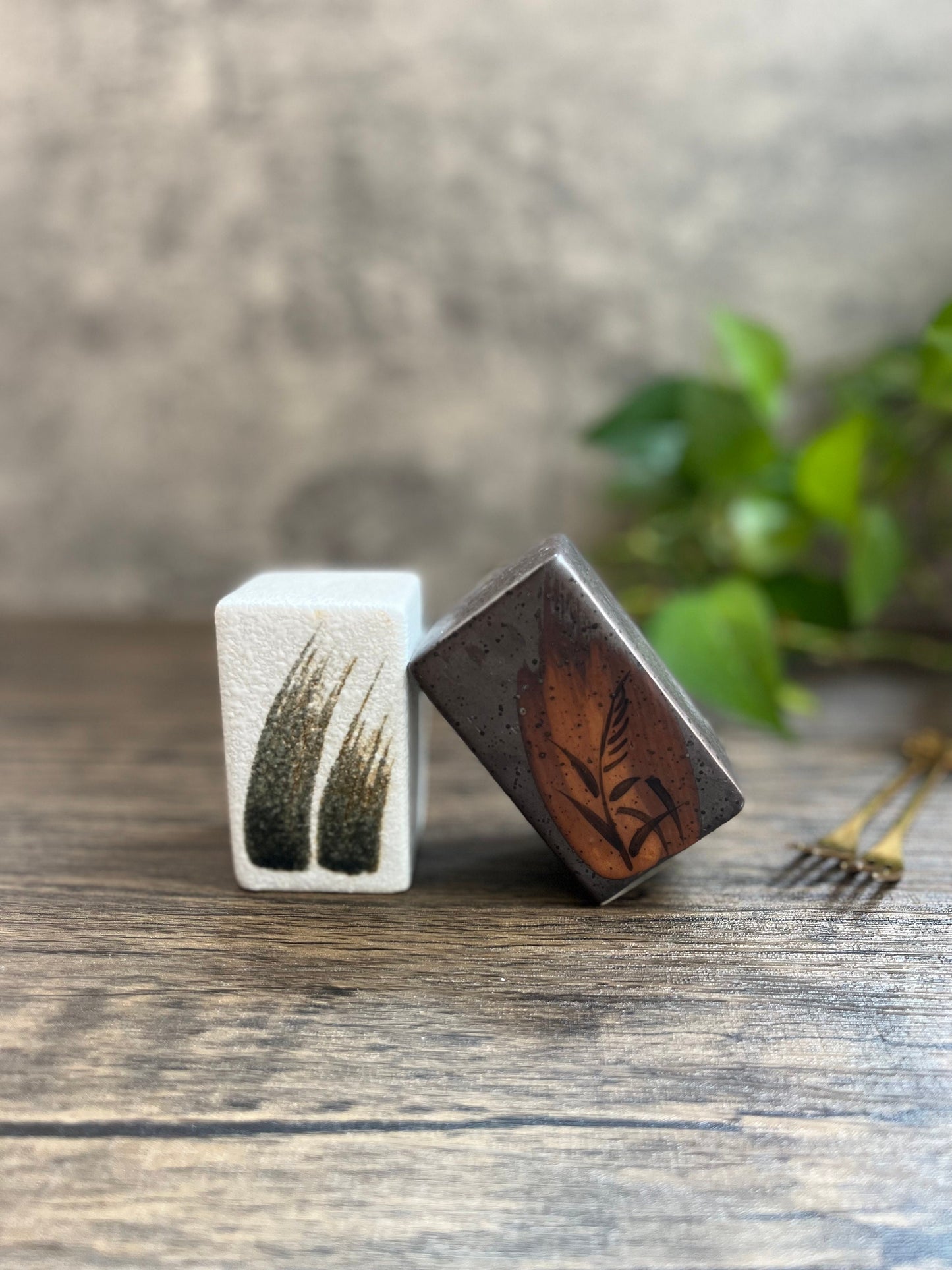 Mini condiment shakers in cube shape, displayed together on rustic wooden surface.