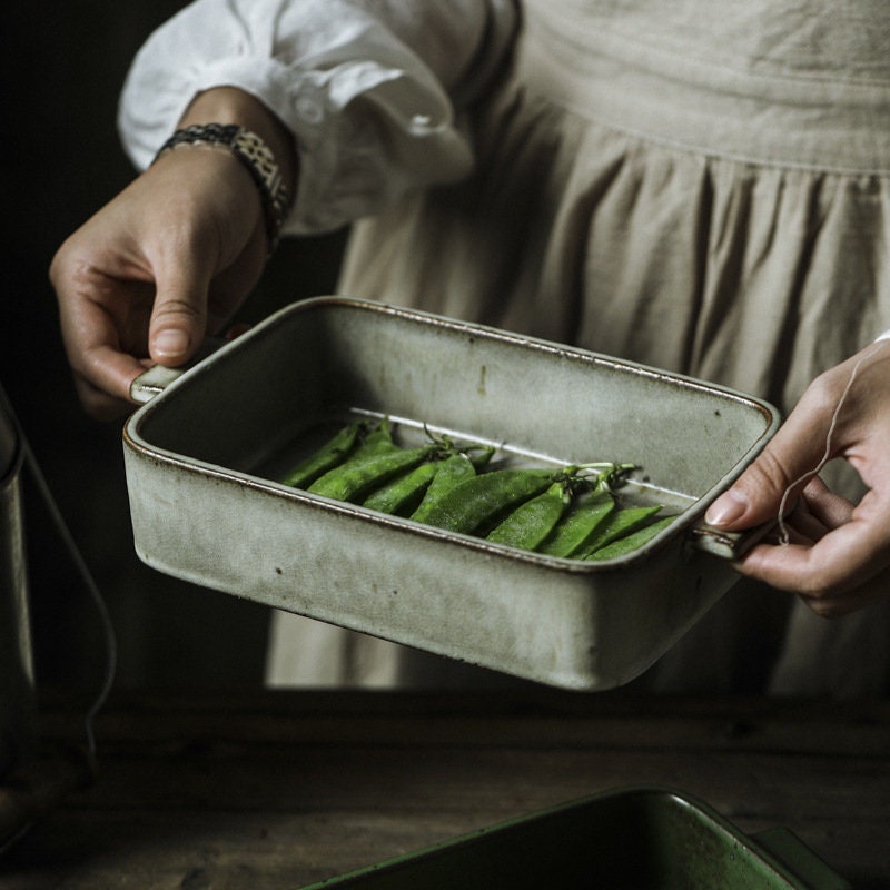Person holding handmade ceramic baking dish with food inside