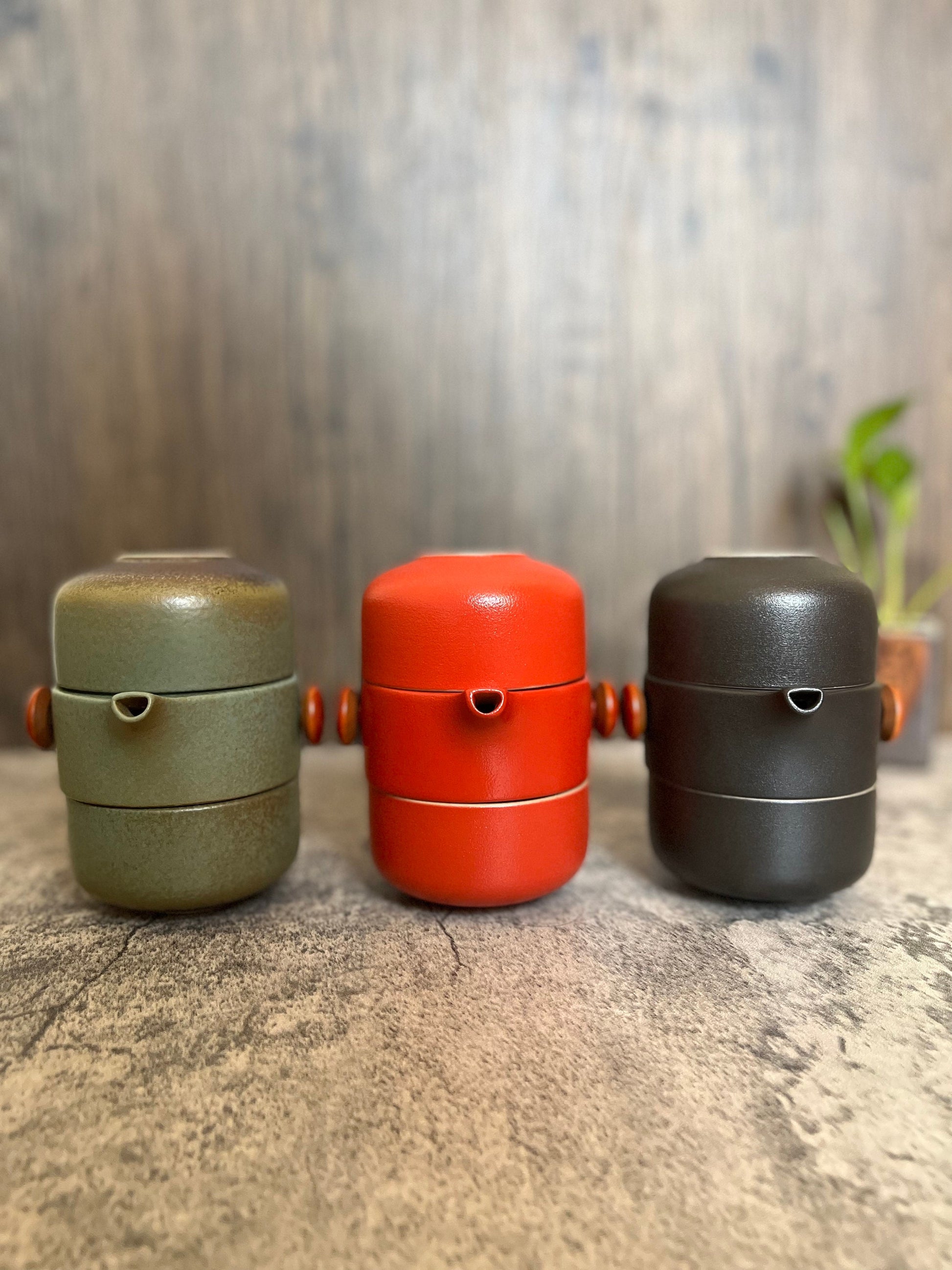 Portable tea brewing set in eco-friendly ceramic clay_all-in-one set with kettle and cups layered and packed together_displaying three available colors_green red and black