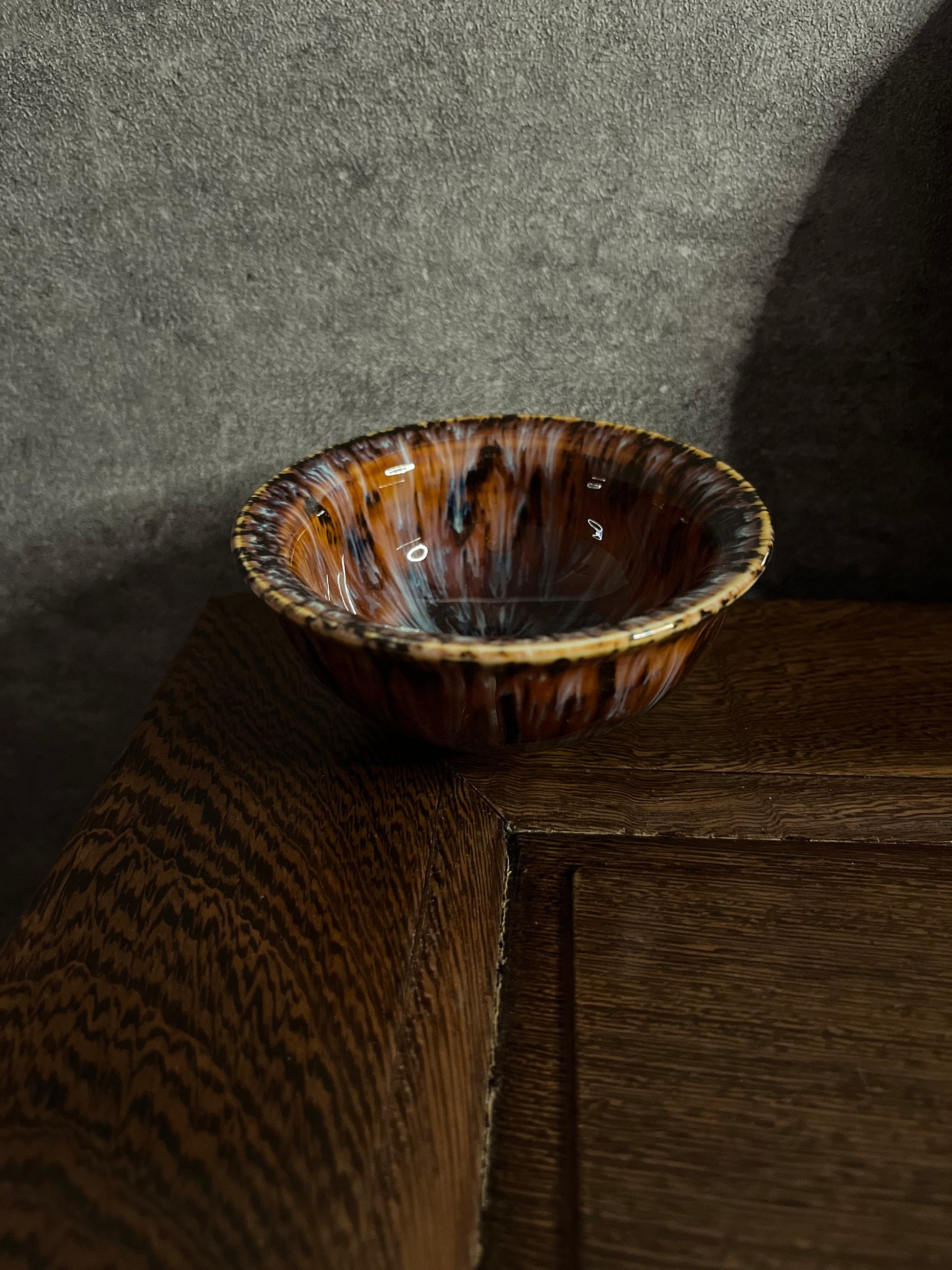 Red-brown ceramic tea cup with glossy finish displayed on wooden table