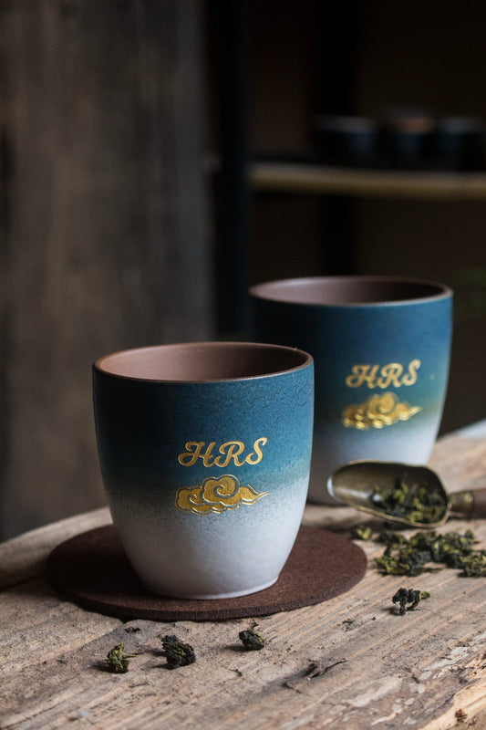 Two retro vintage style sky blue colored ceramic tea cups with personalized gold text with gold cloud design by Home Relax Studio