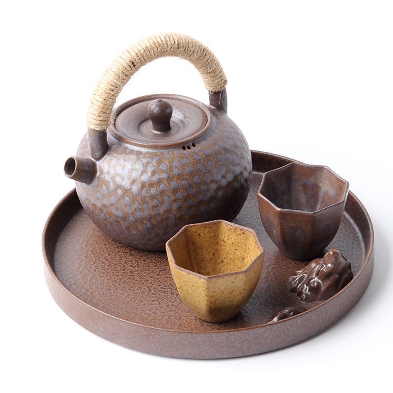 Round ceramic tea plate in silver and reddish brown, displayed with matching teapot and cups.