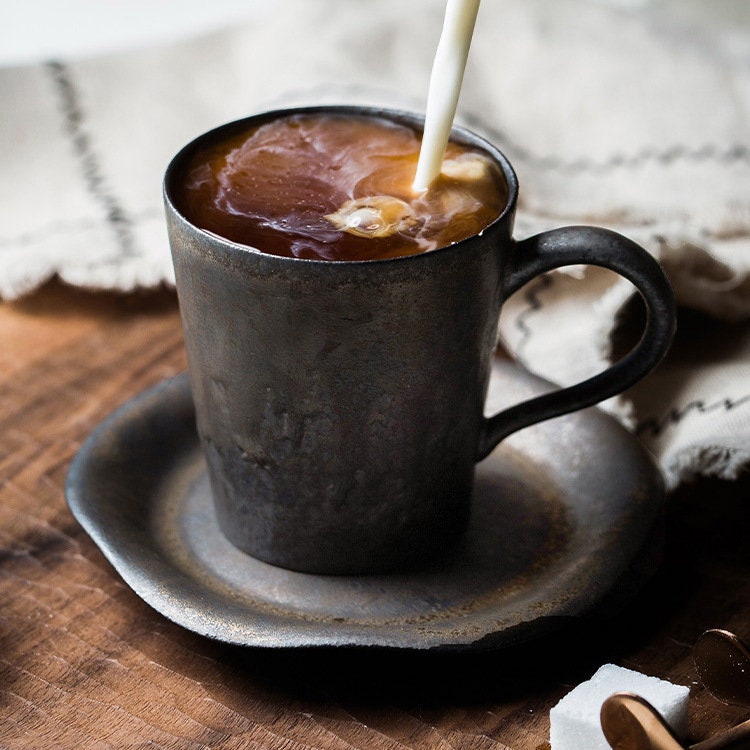 Rustic ceramic espresso cup filled with rich coffee on matching plate