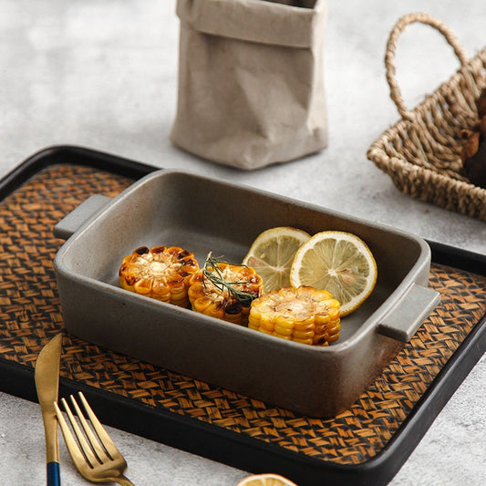 Rustic handmade ceramic baking dish with handles filled with baked food