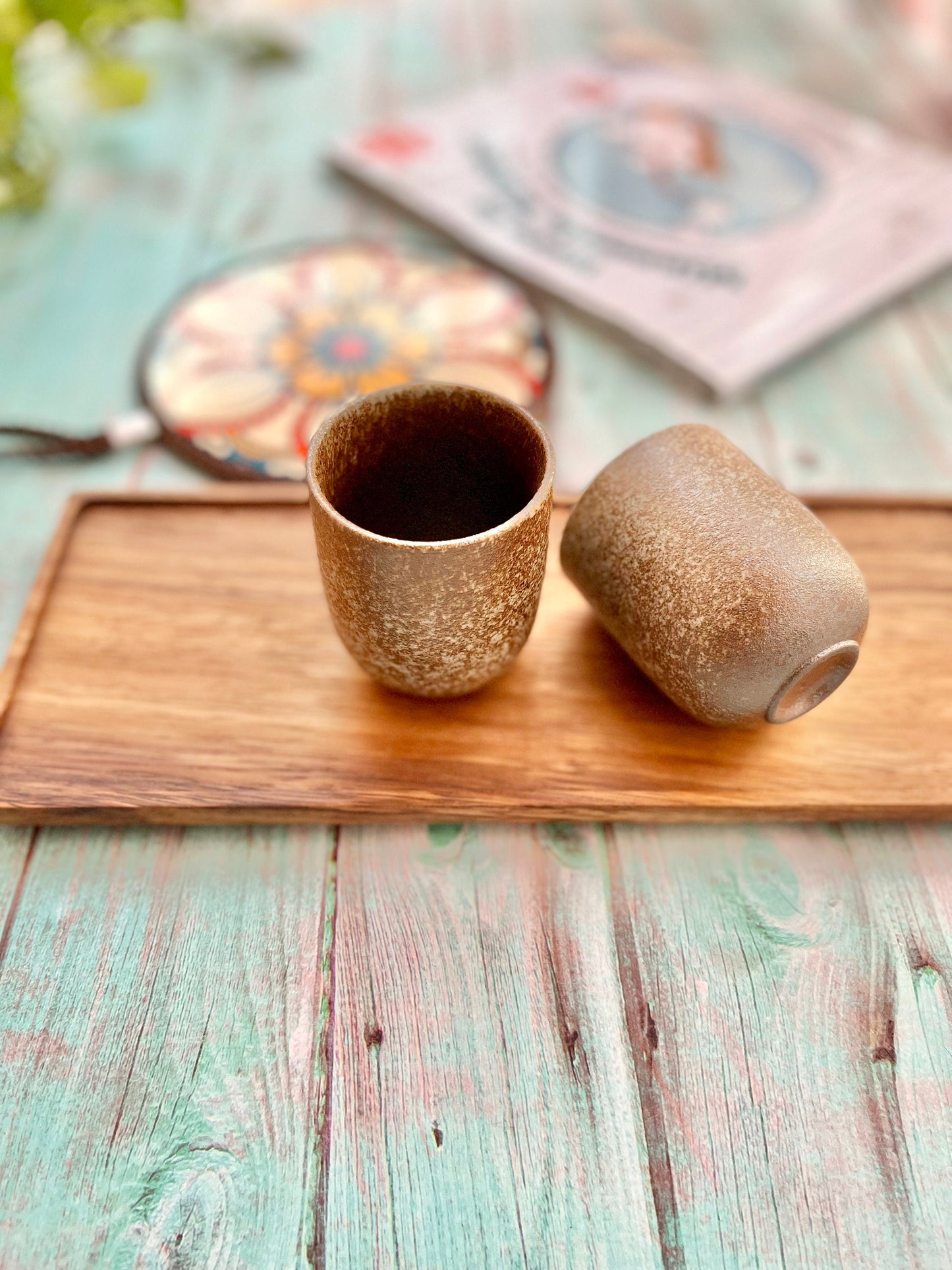 Set of Japanese style ceramic tea cups in warm brown and white glaze, shown with tea on rustic pastel table – Home Relax Studio