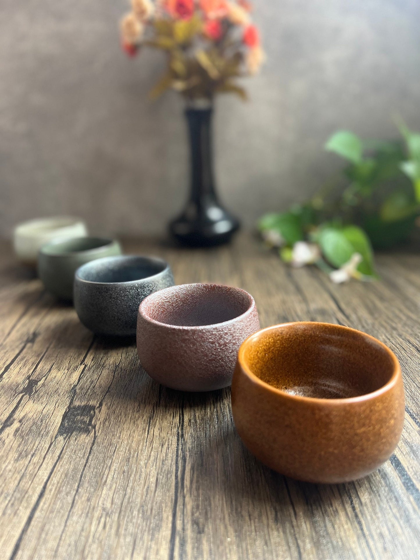 Set of five Japanese ceramic tea cups in different elemental colors displayed on a wooden surface, made by Home Relax Studio.