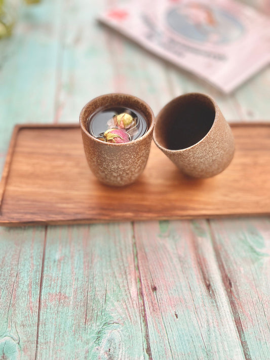 Two minimalist Japanese style ceramic tea cups with speckled glaze on wooden tray, filled with drinkable rose water_styled on pastel blue rustic table – Home Relax Studio