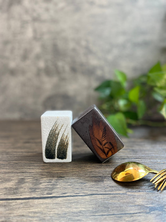 White and brown retro-style ceramic salt and pepper shakers with gold spoon on wooden table, by Home Relax Studio.