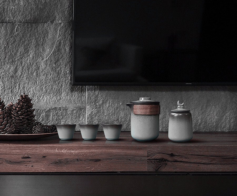White ceramic tea storage jar with wooden lid sleeve along with matching tea kettle and cups in the  set_the set is in a living room with zen vibes